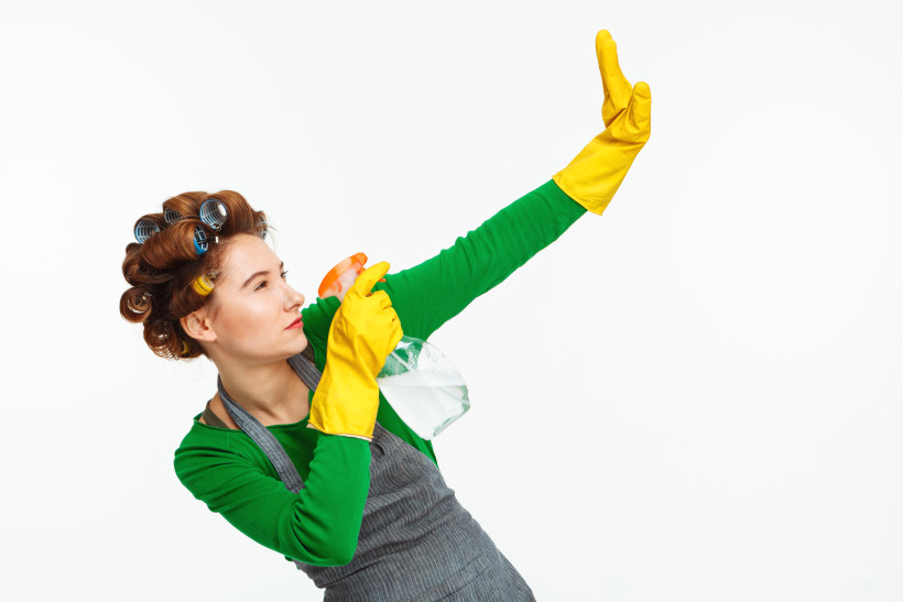 woman spraying windows posing with yellow rubber hands