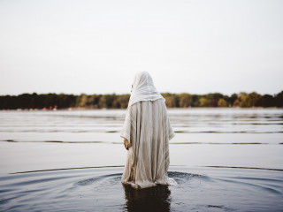 person wearing a biblical robe walking in the water