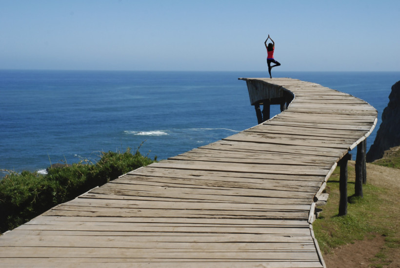 kobieta cwiczaca joge w porcie z pieknym widokiem na ocean