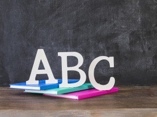 desktop with abc letters books near chalkboard