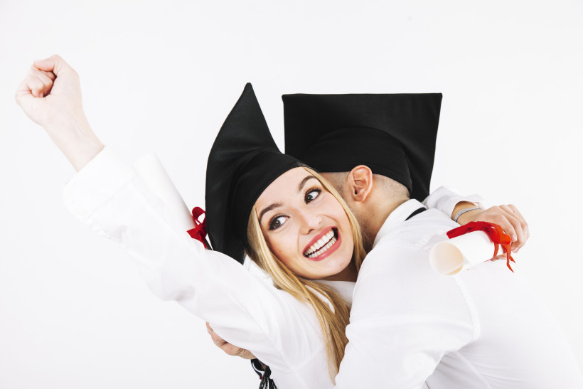 smiling graduating woman embracing with boyfriend